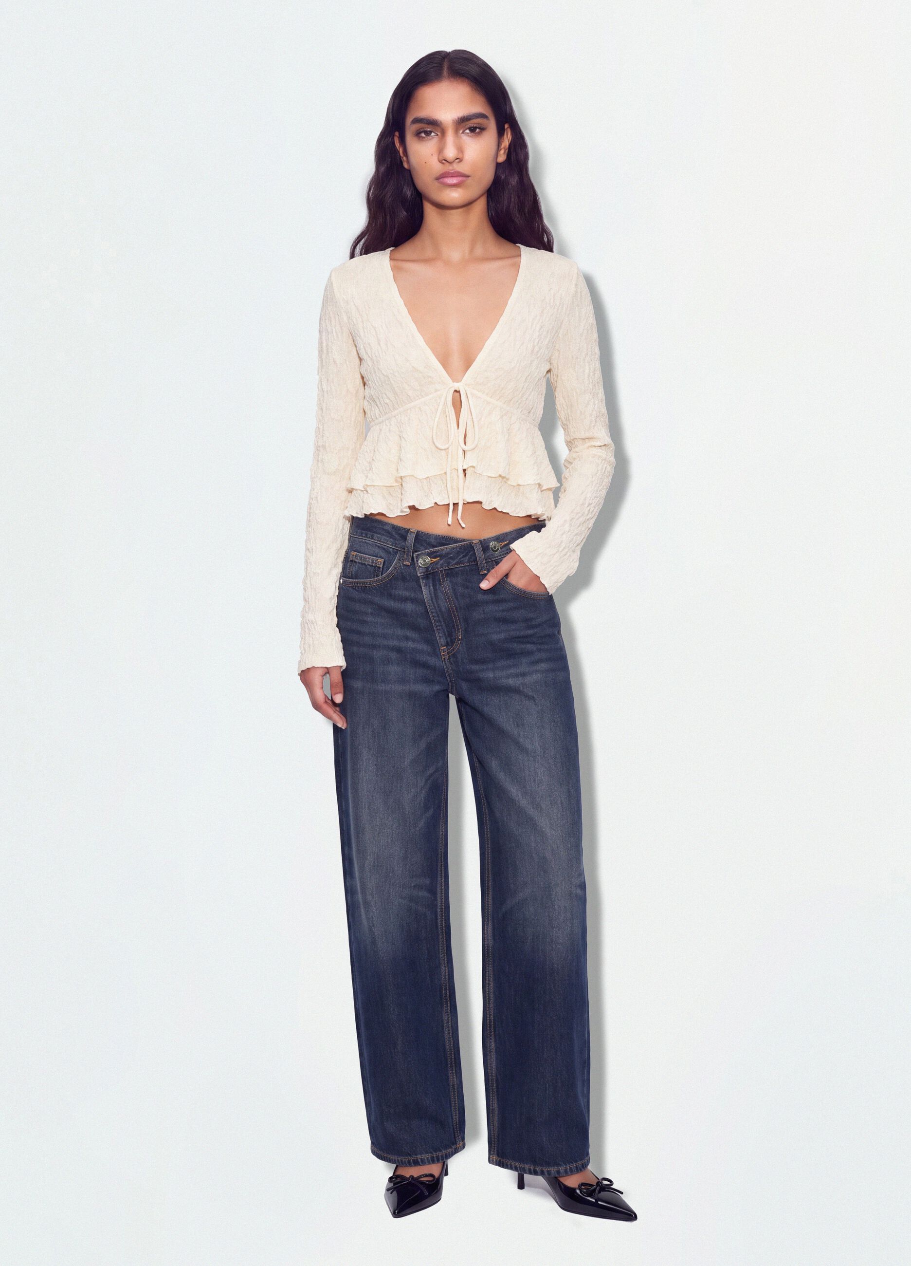 White stretch top with deep V-neck and ruffle trim