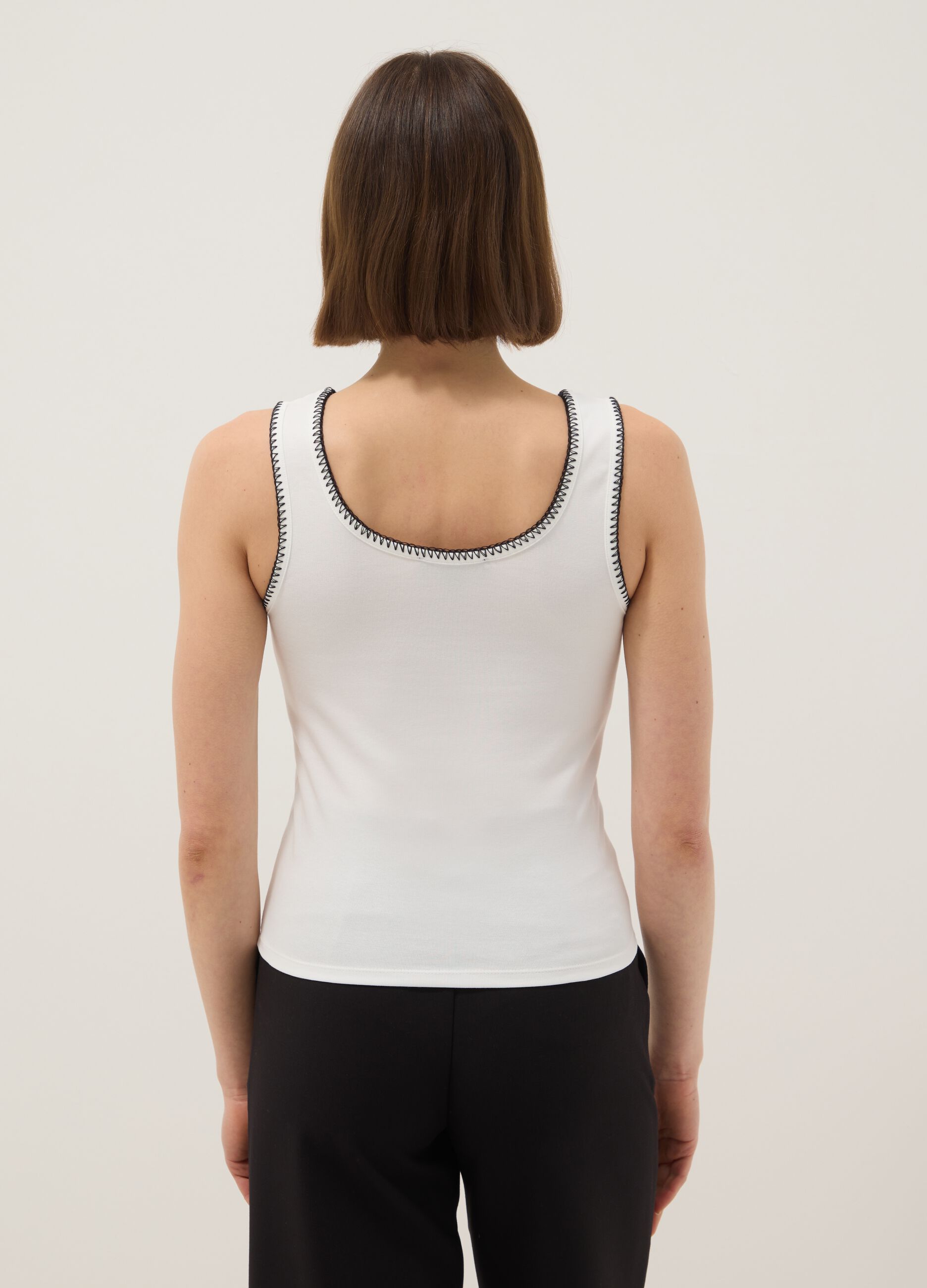 توب كت أبيض من قطن مطاطي بتفاصيل متباينة، بقصة عادية