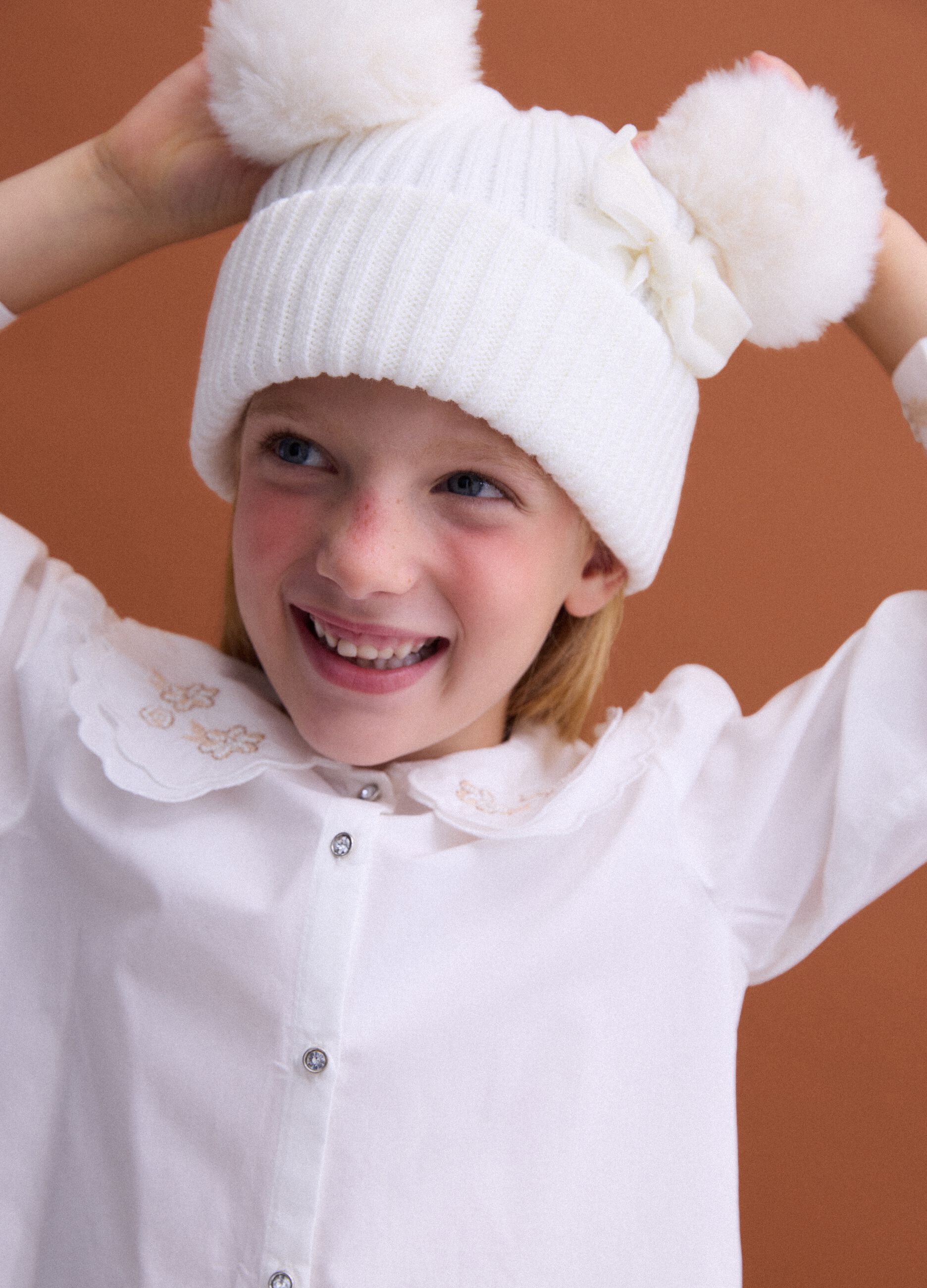 White rib-knit hat with bow and pom-poms